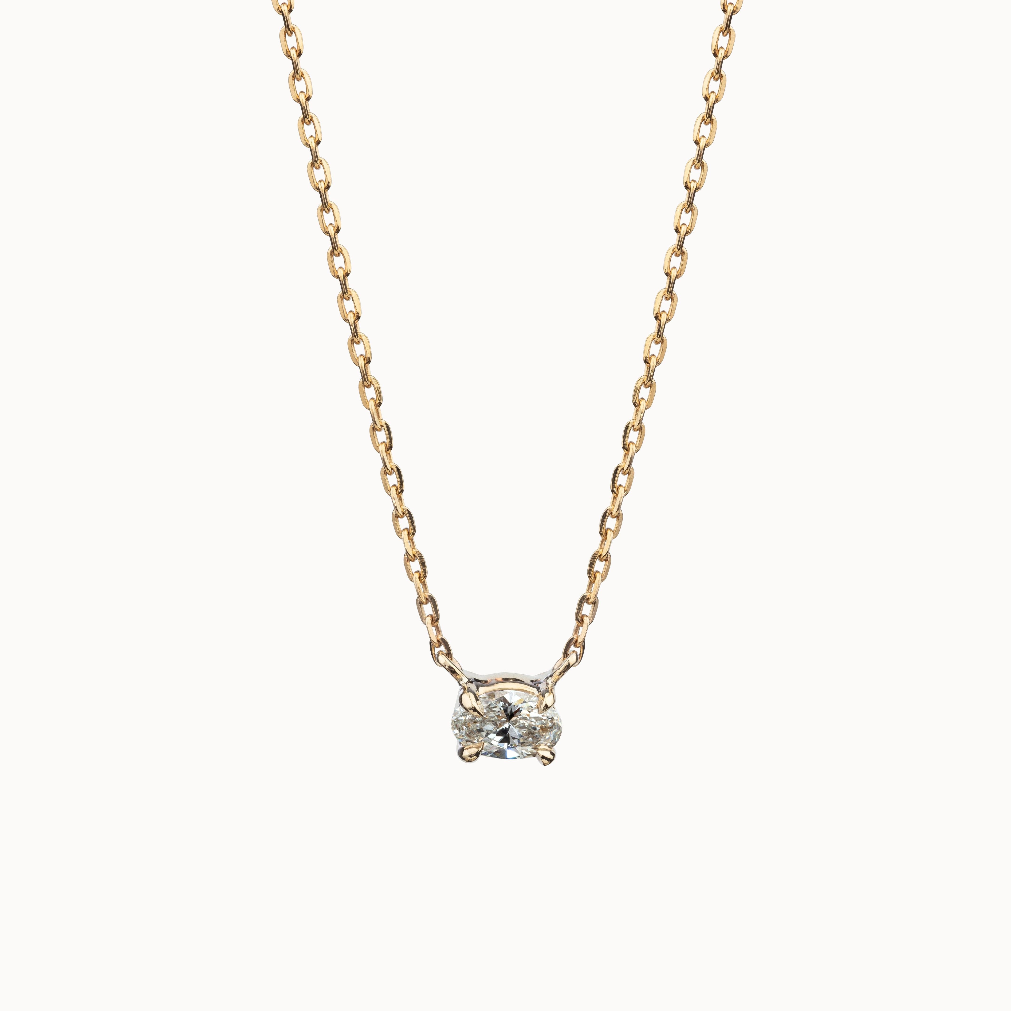 Oval diamond pendant on a gold chain with a white background.